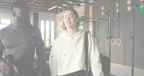 Walking gym partners leaving workout smiling woman in hoodie carrying duffel with trainer