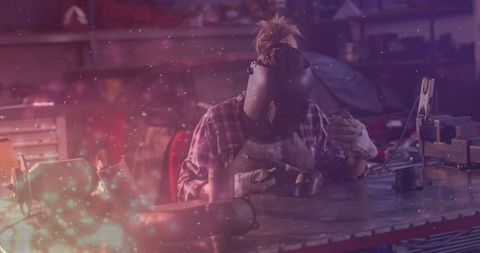 Metalworker Welding Metal Piece with Protective Helmet in Workshop