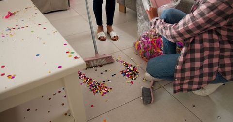Women cleaning confetti after festive celebration at home