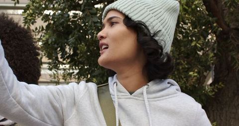 Multicultural friends chatting and gesturing outdoors in beanies and casual hoodies