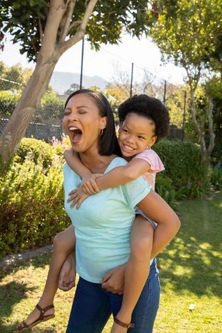 Mother and Daughter Enjoy Piggyback in Sunny Garden