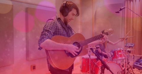 Guitarist and drummer playing in recording studio with warm ambiance