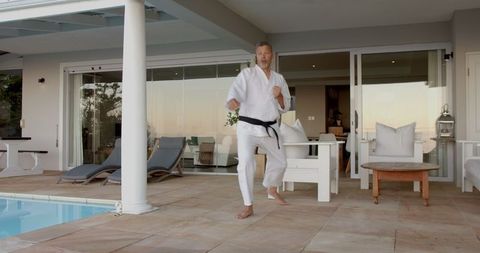 Senior Man Practicing Martial Arts Moves on Sunny Patio