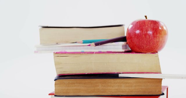 Bright image featuring a stack of books, pencils, and an apple on top. Ideal for use in educational materials, school posters, back-to-school promotions, online courses, teaching resources, and literacy campaigns.