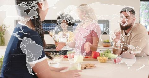 Multicultural friends cooking together around kitchen island with global map overlay