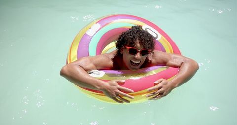 Young man enthusiastically enjoying pool with vibrant float