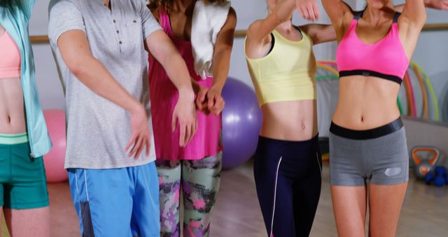 Group of individuals dressed in colorful sportswear in an aerobic exercise class in a gym. Useful for articles, advertisements, or blog posts about fitness programs, group workouts, active lifestyle, or health and wellness activities.