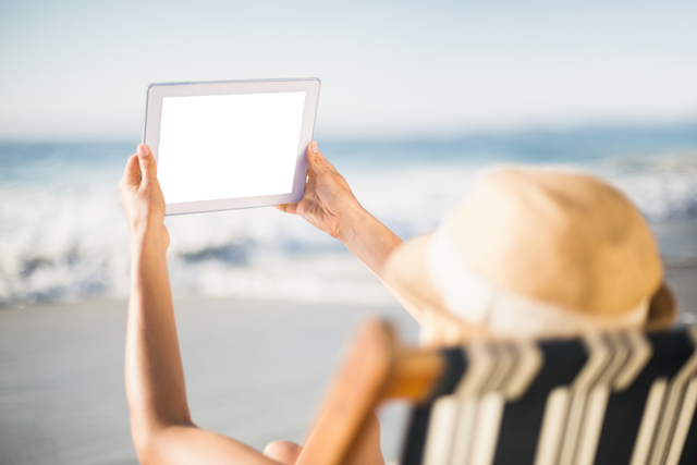 Transparent Screen Tablet Used by Woman on Beach with Sun Hat at Ocean - Download Free Stock Videos Pikwizard.com