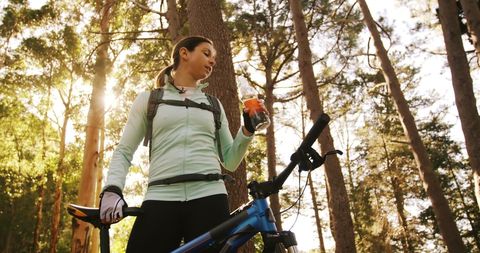 Female Mountain Biker Hydrating in Sunlit Forest - Download Free Stock Images Pikwizard.com