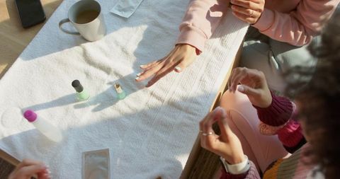 Friends sharing at-home manicure session painting nails in cozy sunlit lounge