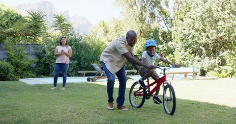 Father Teaching Son Bicycle Riding in Bright Sunny Backyard