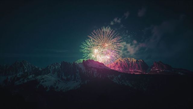 Colorful Fireworks Illuminate Snow-Covered Mountainous Night Landscape