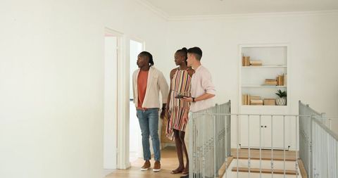 Friends exploring new home hallway smiling