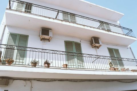 Mediterranean balcony featuring green shutters, wrought iron railings, potted plants