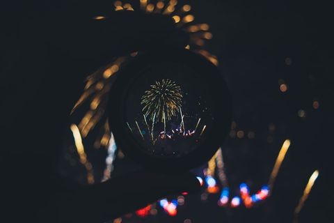Fireworks Reflected Through Circular Lens Held in Hand