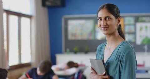 Smiling Female Teacher with Tablet in Engaging Classroom Setting