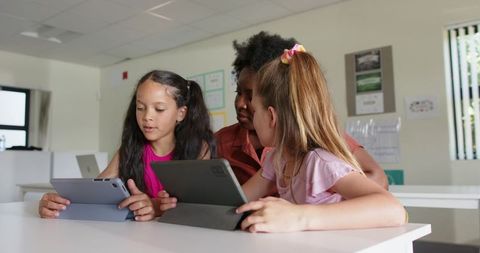 Teacher guiding teen girls using tablets in collaborative classroom learning environment