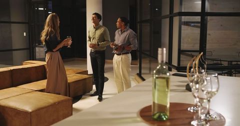 Colleagues Socializing in Modern Office Lounge at Night