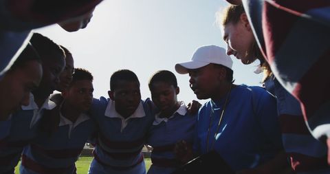 Diverse student team huddles for strategy session on sports field