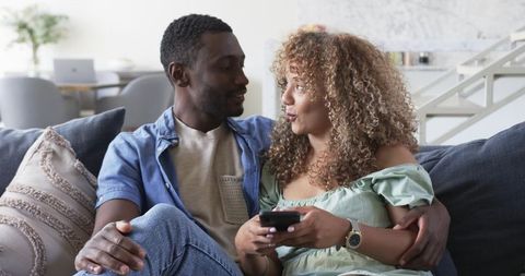 African American Man and Partner Relaxing on Sofa Sharing Remote and Enjoying Cozy Moment