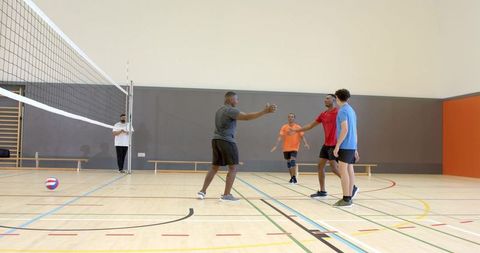 Multicultural male volleyball team giving high-fives on indoor court