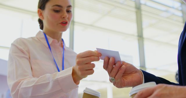 Businesswoman exchanging business card with colleague during coffee break. Ideal for use in corporate communication, networking events promotions, professional relationship building, and articles on the importance of business networking.