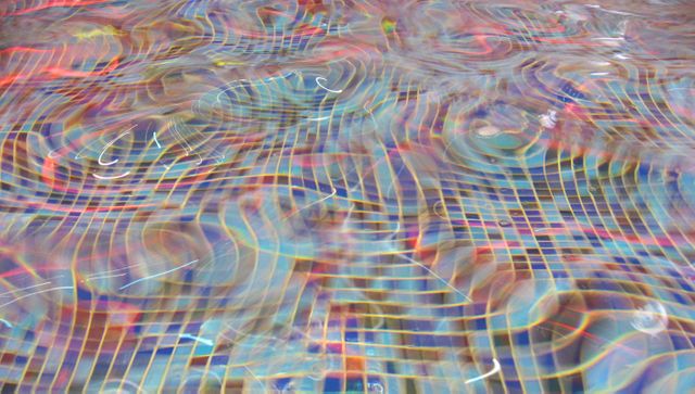A close-up view of water surface in a swimming pool with colorful neon light patterns. Intricate reflections create an abstract, vibrant effect. Perfect for use in design projects, backgrounds, wallpapers, or any visual needing dynamic and energetic water motifs.