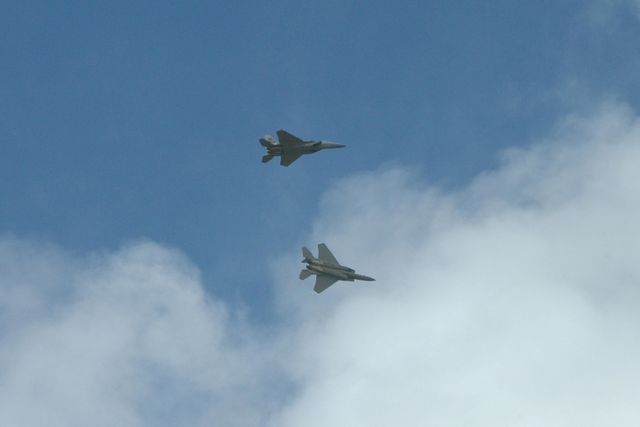 Two U.S. Navy F-18 Super Hornets practicing aerial maneuvers over Kennedy Space Center. Featuring clear skies with some clouds, this scene is part of the World Space Expo, showcasing various aircraft and honoring 50 years of space exploration. Ideal for editorial content, aerospace publications, and aviation events.