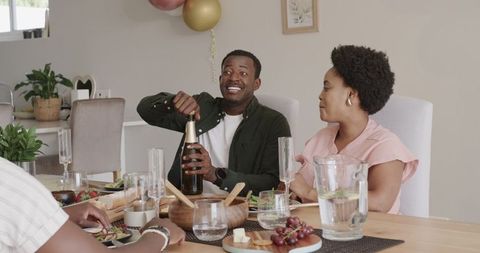 Friends Celebrating with Champagne and Meal Together Indoors