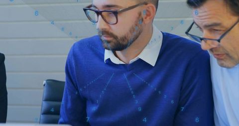 Business team collaborating over laptop with focused bearded man in blue sweater