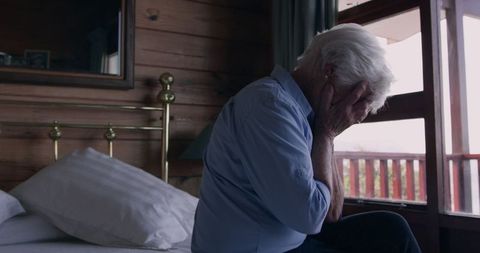 Senior Woman Sad with Hands on Face Sitting on Bed