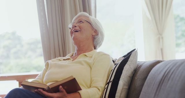 Elderly Woman Laughing While Reading Book at Home - Download Free Stock Images Pikwizard.com