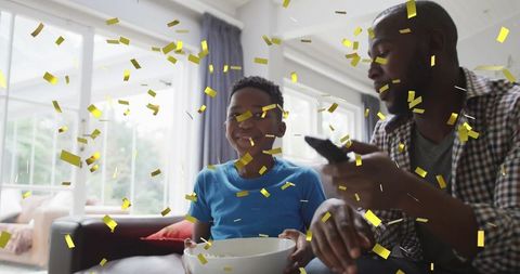 Father and Son Celebrating Victory with Golden Confetti at Home