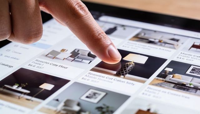 Finger tapping tablet touchscreen showing furniture catalog listing modern lamp prices