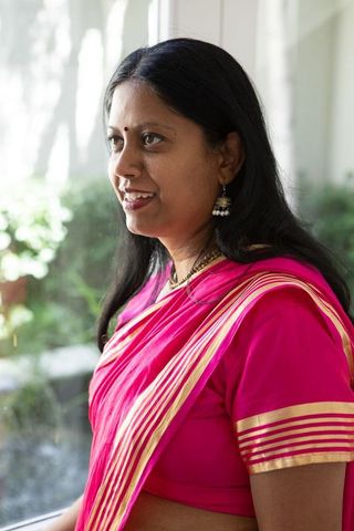 Smiling Indian Woman in Pink Sari with Jhumka Earrings by Window