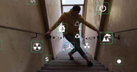 Man wearing hoodie sidestepping in industrial stairwell with eco icons