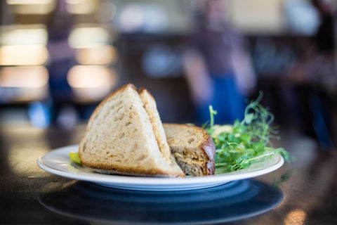 Golden Toasted Sandwich with Melted Cheese and Microgreens on White Plate, Cafe