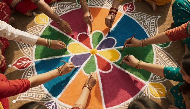 Women creating vibrant rangoli wearing sarees and bangles top view festival collaboration