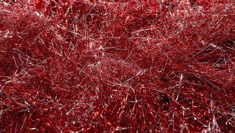 Red metallic tinsel close-up with silver strands and sparkling glitter texture