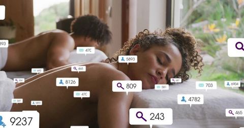 Curly woman receiving couples massage with floating digital notifications, wellness calm
