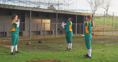 Female softball team stretching before game in athletic green uniforms