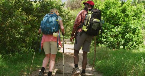 Happy Diverse Couple Hiking with Backpacks in Lush Green Park - Download Free Stock Images Pikwizard.com