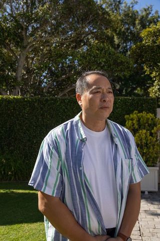 Asian Man in Sunlit Garden Observing his Watch