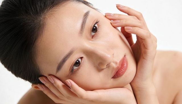 Closeup asian woman with dewy skin and manicured nails touching face beauty portrait