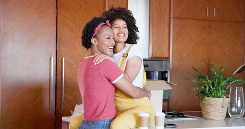 Joyful Lesbian Couple Embracing in Cozy Kitchen Setting