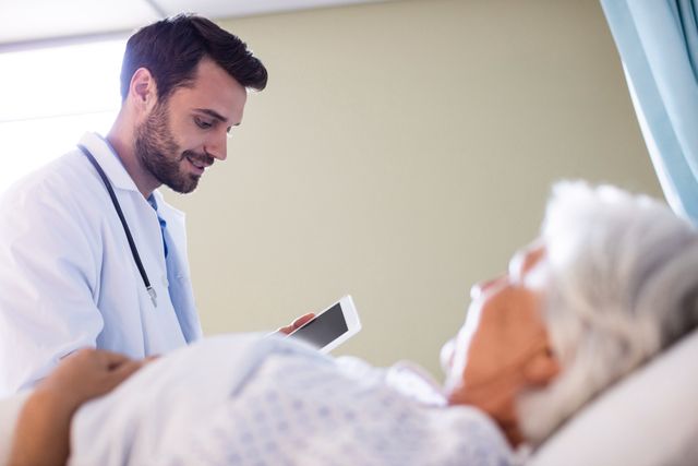 This image can be used in healthcare-related articles, medical websites, hospital brochures, and patient care guides. It highlights the interaction between a healthcare professional and a senior patient, emphasizing the use of modern technology in medical consultations.