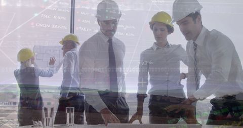 Engineers collaborating with stock market data overlay