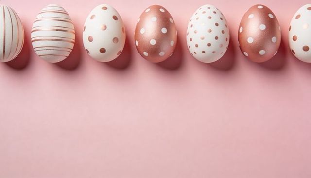 Rose gold and white polka dot eggs lining pastel pink backdrop with soft studio shadows