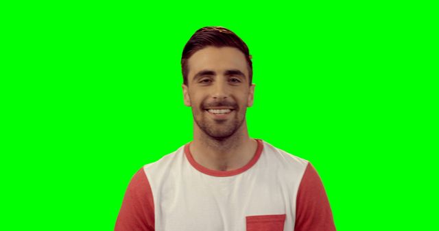 Man is smiling warmly in this portrait, wearing casual red and white t-shirt against green background. Useful for content creators, graphic designers, and advertisers, it is perfect for presentations, promotional materials, and web design projects.