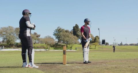 Cricket Players Strategizing During Local Match on Sunny Field